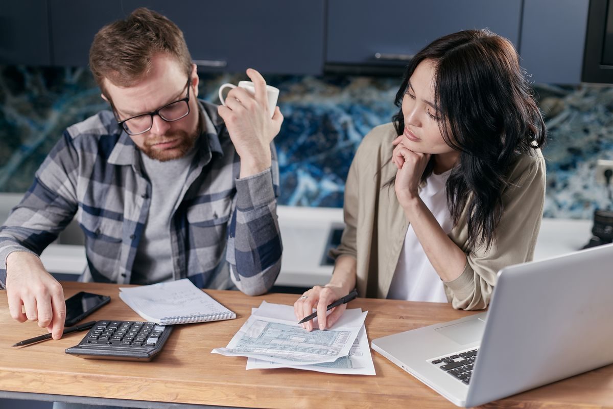 A person planning a car budget at a table with a calculator, notebook, and paperwork