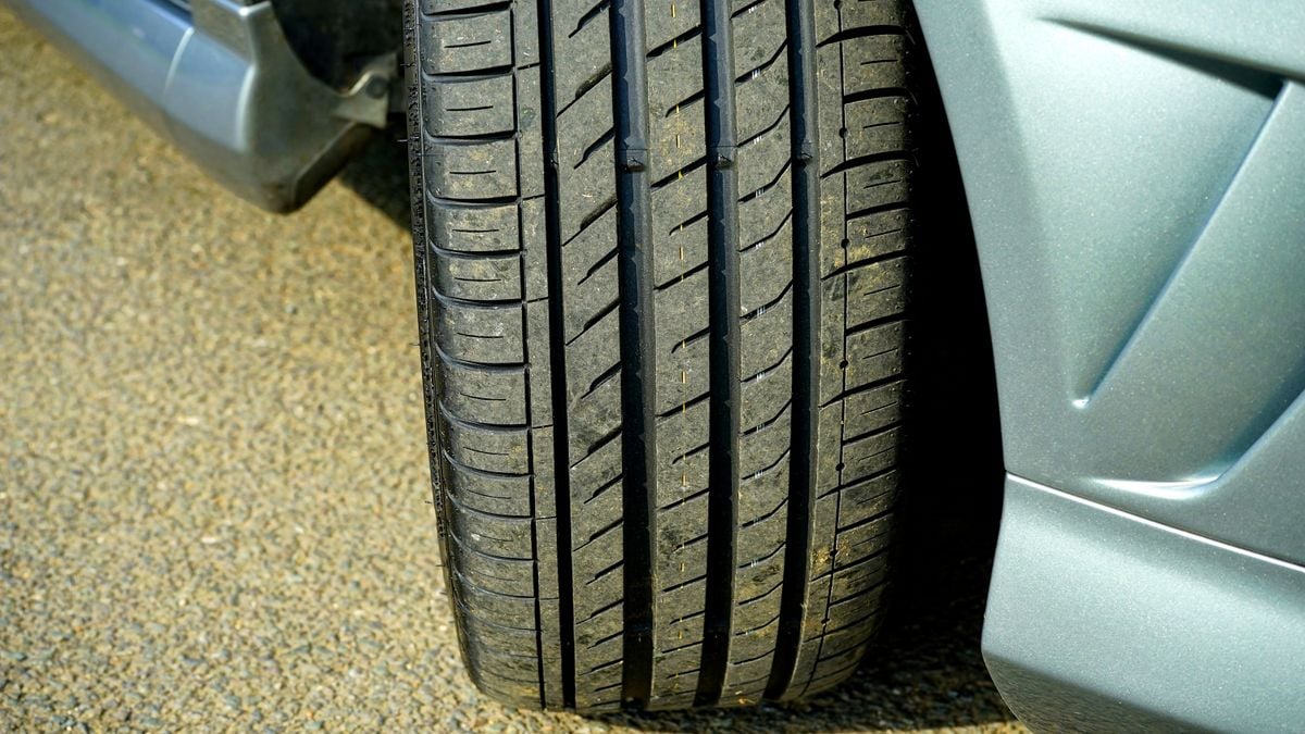 Close-up of a used car tire tread being inspected on asphalt