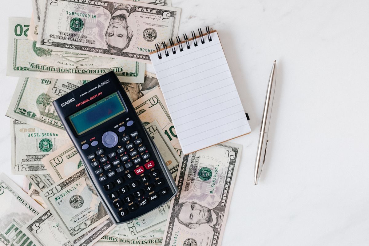 A calculator resting on financial paperwork used to add up the true monthly cost of a car