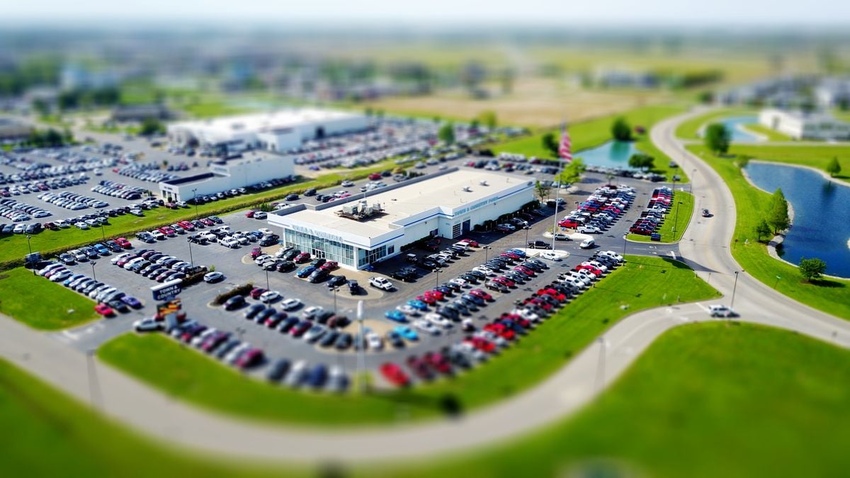 Aerial view of a used car dealership surrounded by rows of parked vehicles in a suburban setting