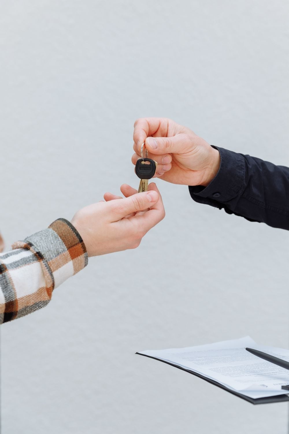 A dealer handing car keys to a buyer over a signed purchase contract