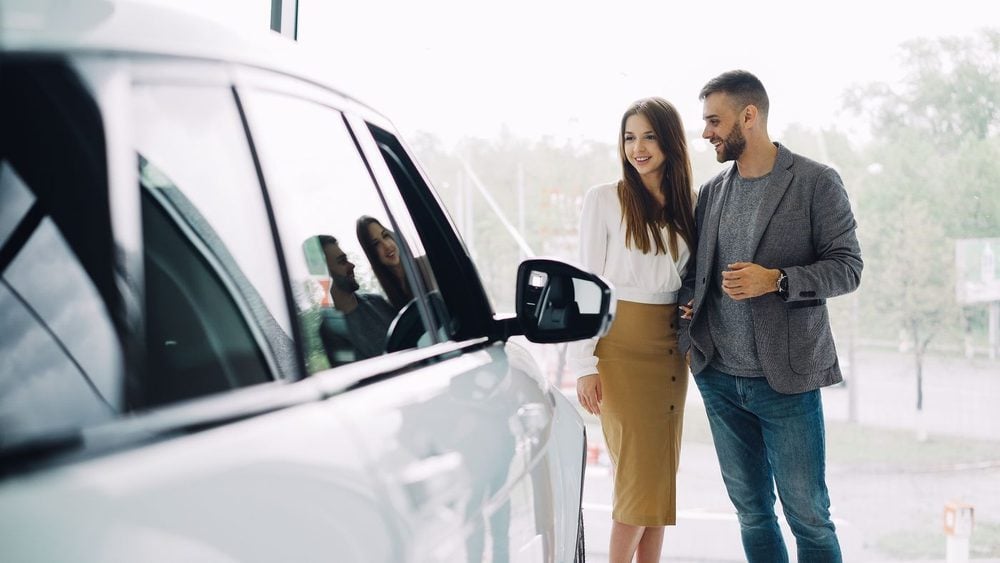A couple comparing a used car at a Dallas–Fort Worth dealership