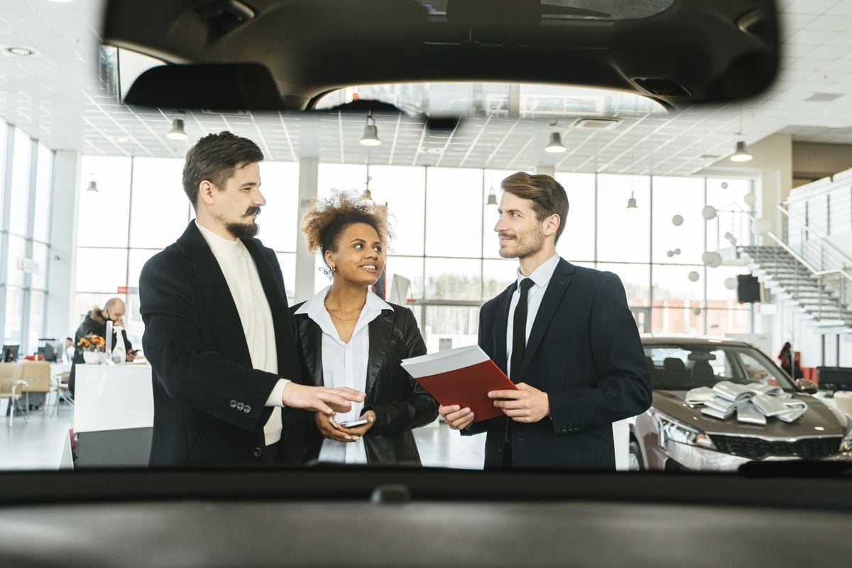 A couple reviewing auto financing paperwork with a dealership representative