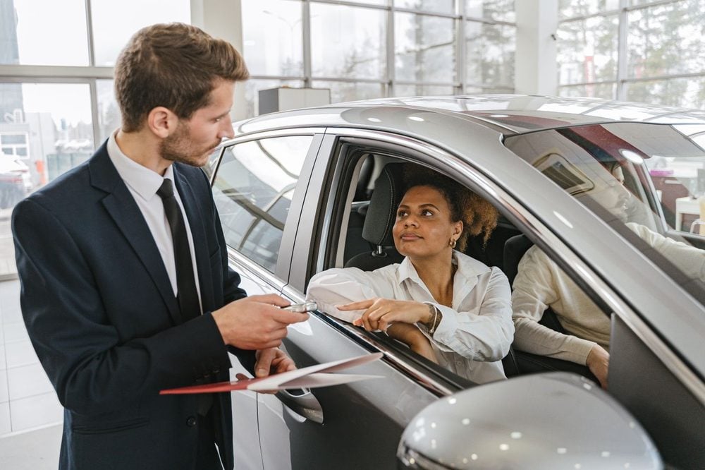 A salesperson handing car keys to a customer after a purchase